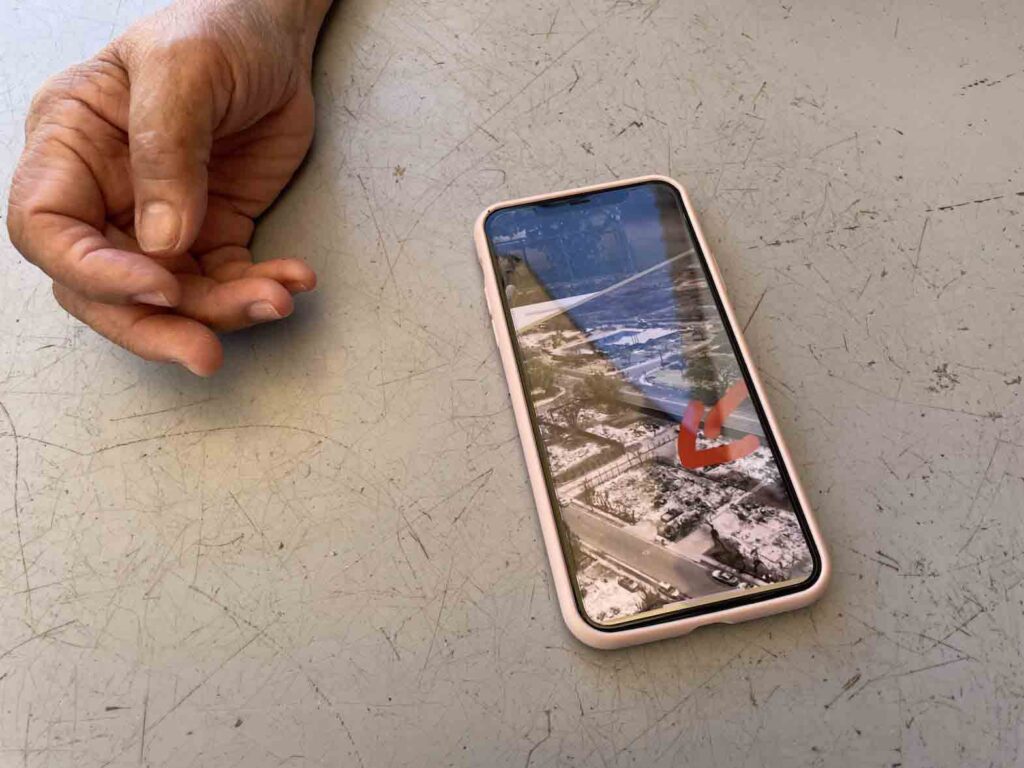 Mila Lat shows an aerial image of her burned home in Lahaina on cellphone. (Madeleine List/Civil Beat/2023)